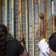 Two children look through gaps in a border wall, highlighting the difficult crossing experience for migrants. Two children look through gaps in a border wall, highlighting the difficult crossing experience for migrants.