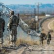 Soldiers patrolling along a barbed-wire border fence near the U.S.-Mexico border. Soldiers patrolling along a barbed-wire border fence near the U.S.-Mexico border.
