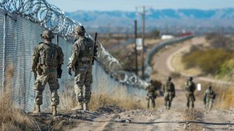 Soldiers patrolling along a barbed-wire border fence near the U.S.-Mexico border.