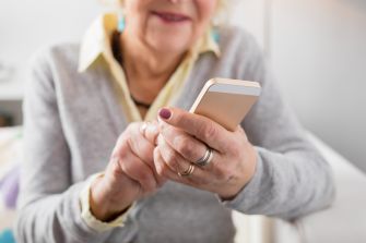 An elderly woman using a smartphone, illustrating the target demographic in a telemarketing fraud case.