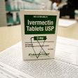 A box of Ivermectin tablets on a pharmacy counter, with prescription paperwork in the background. A box of Ivermectin tablets on a pharmacy counter, with prescription paperwork in the background.