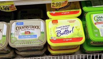 Container of "I Can’t Believe It’s Not Butter!" alongside other butter substitutes on a grocery store shelf.