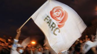 A person holding a white flag featuring the FARC logo during a protest or demonstration.