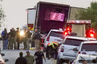 Emergency responders and law enforcement officials investigate a semi-truck after discovering deceased migrants inside near San Antonio, Texas.
