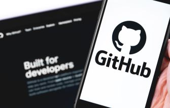 A person holding a smartphone displaying the GitHub logo, with the GitHub website in the background.