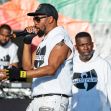 A performer rapping on stage with members of Wu-Tang Clan in the background. A performer rapping on stage with members of Wu-Tang Clan in the background.