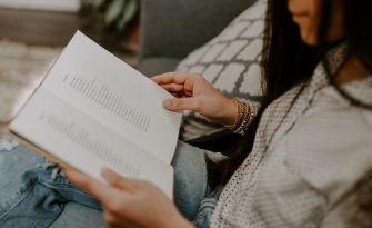 A person reading a book while seated, focusing on the pages.