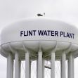 Water tower marked "Flint Water Plant" against a cloudy sky. Water tower marked "Flint Water Plant" against a cloudy sky.