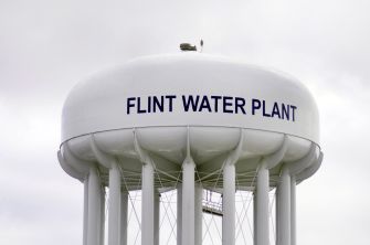 Water tower marked "Flint Water Plant" against a cloudy sky.