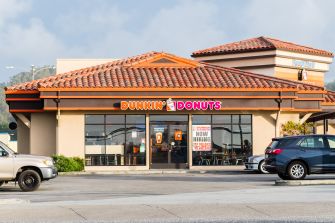 Exterior of a Dunkin' Donuts location with a "Now Hiring" banner displayed.