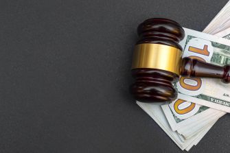 Gavel resting on a pile of cash, symbolizing legal proceedings and financial fraud.