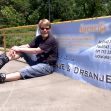 Former Slovenian Olympic figure skater Luka Klasinc sitting on skates beside a promotional banner. Former Slovenian Olympic figure skater Luka Klasinc sitting on skates beside a promotional banner.