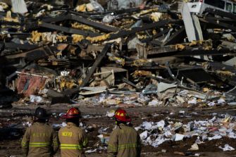Firefighters survey the wreckage of the Mayfield Consumer Products candle factory, which was destroyed by a tornado, resulting in multiple fatalities.