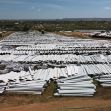 Aerial view of a large area filled with discarded wind turbine blades stacked in rows. Aerial view of a large area filled with discarded wind turbine blades stacked in rows.