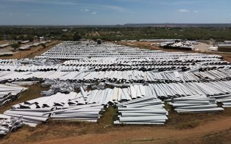 Aerial view of a large area filled with discarded wind turbine blades stacked in rows.