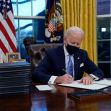 President Joe Biden signing executive orders in the Oval Office on his first day in office, wearing a mask and surrounded by stacks of documents. President Joe Biden signing executive orders in the Oval Office on his first day in office, wearing a mask and surrounded by stacks of documents.