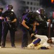 Police officers interact with a protester on the ground amidst a tense scene during the 2020 demonstrations in response to police brutality. Police officers interact with a protester on the ground amidst a tense scene during the 2020 demonstrations in response to police brutality.