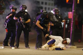 Police officers interact with a protester on the ground amidst a tense scene during the 2020 demonstrations in response to police brutality.