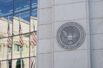 Seal of the U.S. Securities and Exchange Commission on a building with reflections of American flags in the windows.