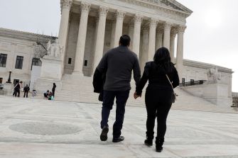 A couple walking hand in hand towards the Supreme Court building.