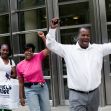 Group of people celebrating outside a building, raising their fists in solidarity and joy. Group of people celebrating outside a building, raising their fists in solidarity and joy.