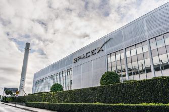SpaceX building with logo and surrounding greenery.