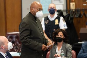 Two men standing in a courtroom during their exoneration proceedings for the assassination of Malcolm X.