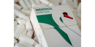 A pack of menthol cigarettes labeled "Menthol Extra Slim" surrounded by white cigarette filters.