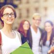 A group of college students smiling and walking on campus, holding school supplies. A group of college students smiling and walking on campus, holding school supplies.
