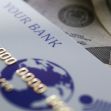 A bank card on top of cash and coins, symbolizing financial fraud. A bank card on top of cash and coins, symbolizing financial fraud.