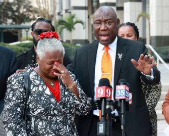A civil rights attorney speaks during a press conference alongside a woman visibly emotional after filing a lawsuit against a Central Florida credit union.