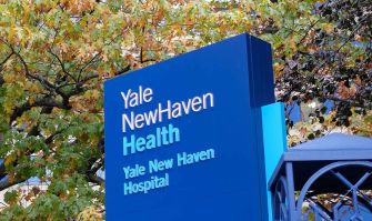 Sign for Yale New Haven Health and Yale New Haven Hospital with autumn foliage in the background.