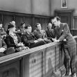 A black and white court scene featuring a judge, jurors, and an attorney speaking to the jury in a courtroom. A black and white court scene featuring a judge, jurors, and an attorney speaking to the jury in a courtroom.