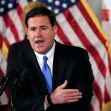 Governor Doug Ducey of Arizona speaking at a press conference, with American flags in the background. Governor Doug Ducey of Arizona speaking at a press conference, with American flags in the background.