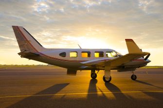 A small Piper PA28 aircraft on the runway at sunset.