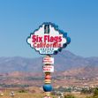 Sign for Six Flags California featuring attractions and a gift shop, set against a mountainous backdrop. Sign for Six Flags California featuring attractions and a gift shop, set against a mountainous backdrop.