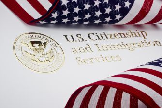 U.S. Citizenship and Immigration Services emblem with American flag ribbon.
