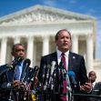 Texas officials speaking at a podium with microphones in front of a large government building. Texas officials speaking at a podium with microphones in front of a large government building.
