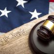 A gavel resting on a document with the words "We the People," set against an American flag background. A gavel resting on a document with the words "We the People," set against an American flag background.