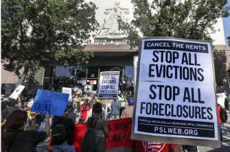 Protesters rally outside a courthouse holding signs advocating to cancel rents and stop evictions and foreclosures.