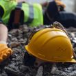 Construction helmet on rubble with an injured worker in the background. Construction helmet on rubble with an injured worker in the background.