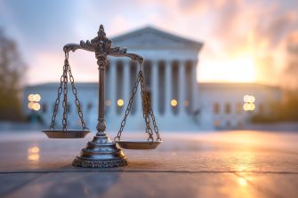 A scale of justice in front of the U.S. Supreme Court building at sunset.