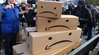 Stacked cardboard boxes with sad face designs, representing the Make Amazon Pay campaign.