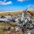 Wreckage of a helicopter crash site in a grassy landscape, with debris scattered under a blue sky. Wreckage of a helicopter crash site in a grassy landscape, with debris scattered under a blue sky.