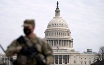 A soldier in the foreground with the U.S. Capitol building in the background.
