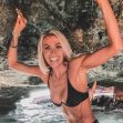 A fit woman posing under a rock formation, smiling and wearing a bikini. A fit woman posing under a rock formation, smiling and wearing a bikini.