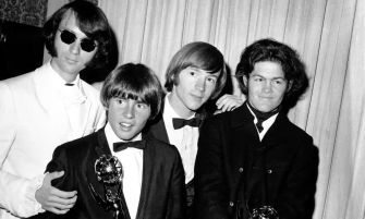 The Monkees gathered together, dressed in suits at an event, celebrating their musical achievements.