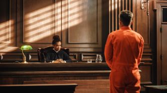 A judge listens to a man in an orange jumpsuit during a court proceeding.