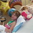 A young girl recovering in a hospital bed surrounded by stuffed animals and get well balloons. A young girl recovering in a hospital bed surrounded by stuffed animals and get well balloons.