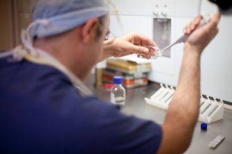 A medical professional handling laboratory equipment in a fertility clinic setting.